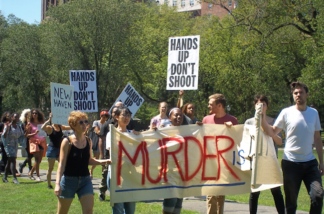 Protesters marched behind a larger banner reading "Murder is Illegal". (Photo credit: Reappropriate)