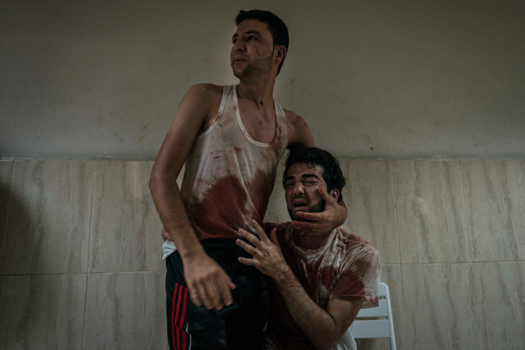 Two brothers grieve the death of their father at Nasser hospital, following an Israeli airstrike that destroyed the family home. (Photo credit: Sergey Ponomarev / The New York Times)