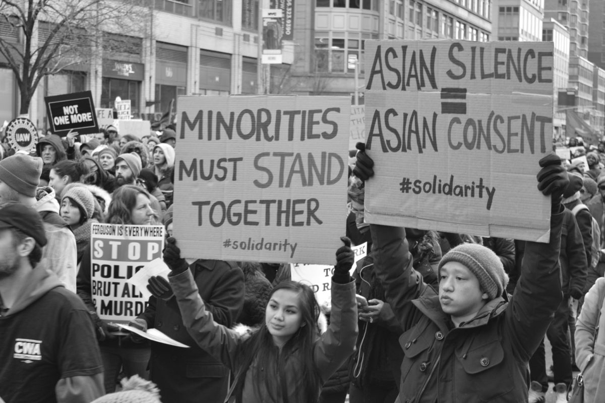 Asian Americans hold signs at a protest. (Photo credit: Flickr / Marcela McGreal)